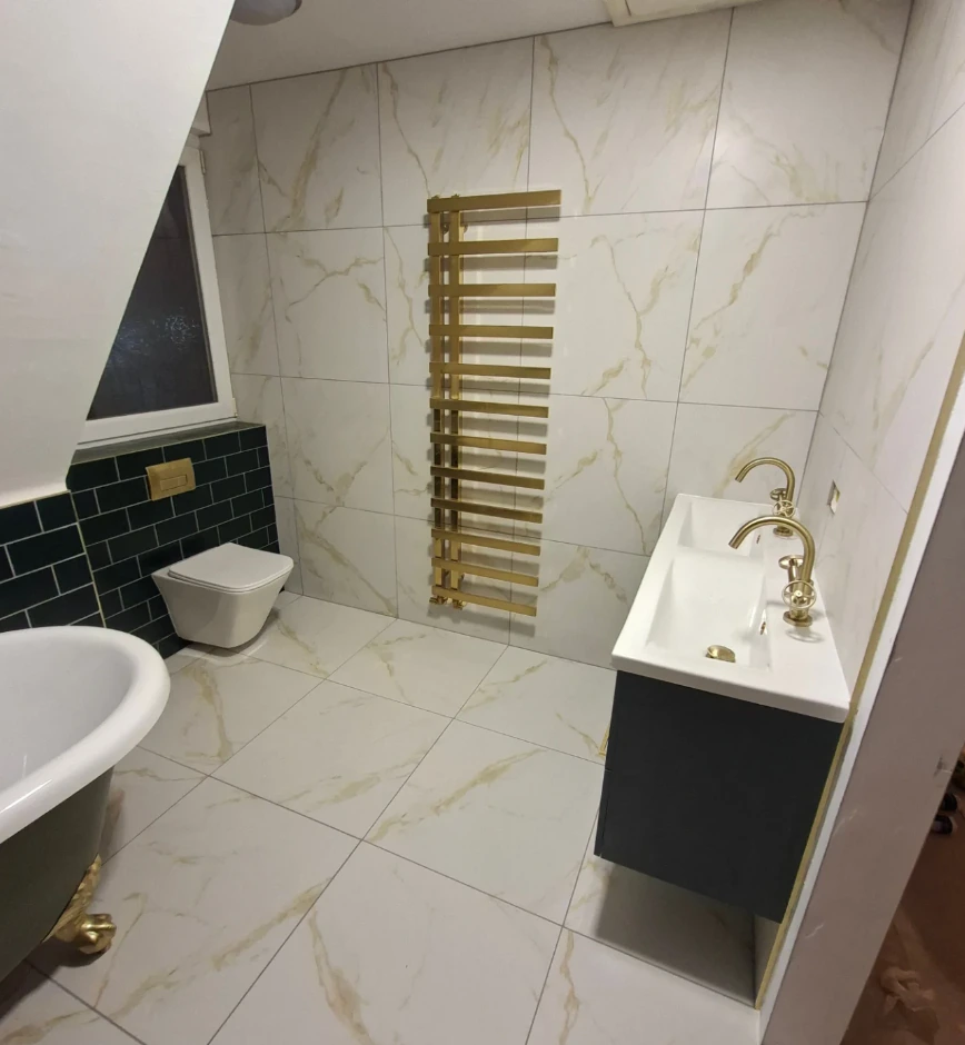 Modern bathroom with marble-effect tiling, dark vanity, gold fittings and a freestanding bath