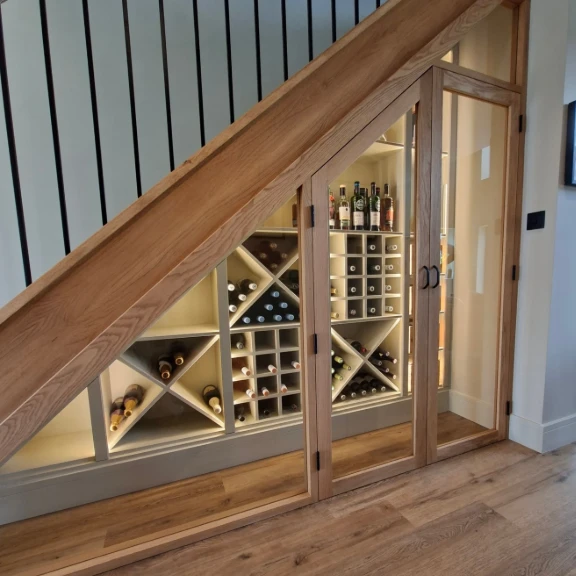 Oak under-stairs wine storage with glass doors and lit shelving